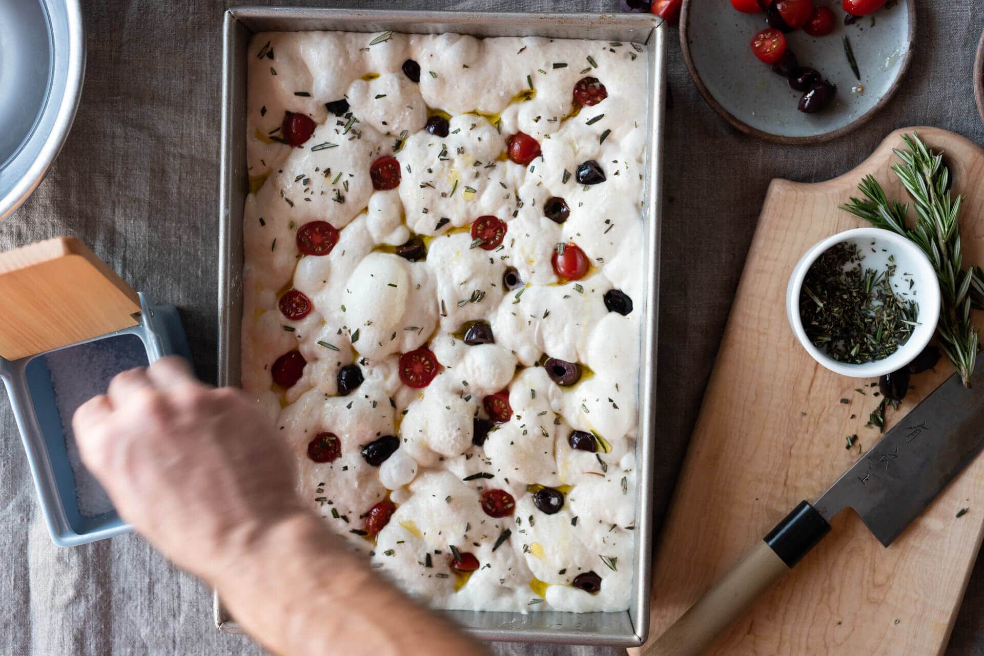 Topping focaccia with herbs and salt