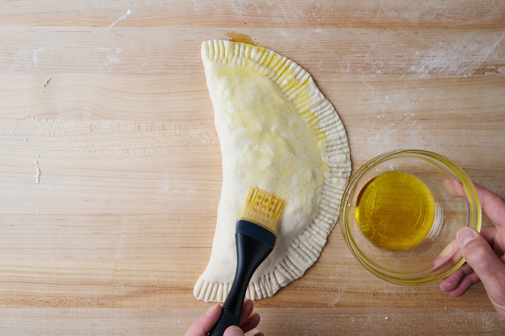 Brush calzone dough with olive oil