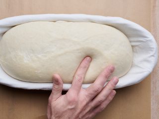 Performing the poke test to determine when dough is fully proofed