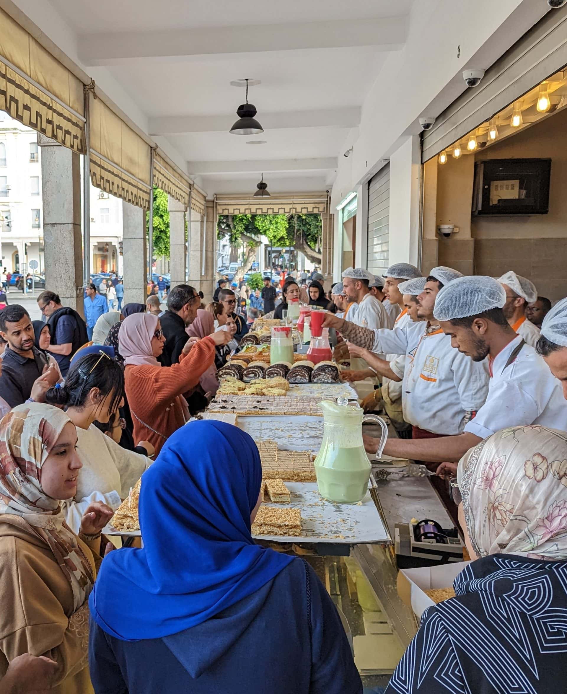 Citizens of Rabat crowding a French-influenced pastry stand.