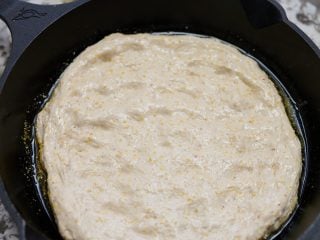 Pressing out pizza dough to fit skillet (Dutch oven).