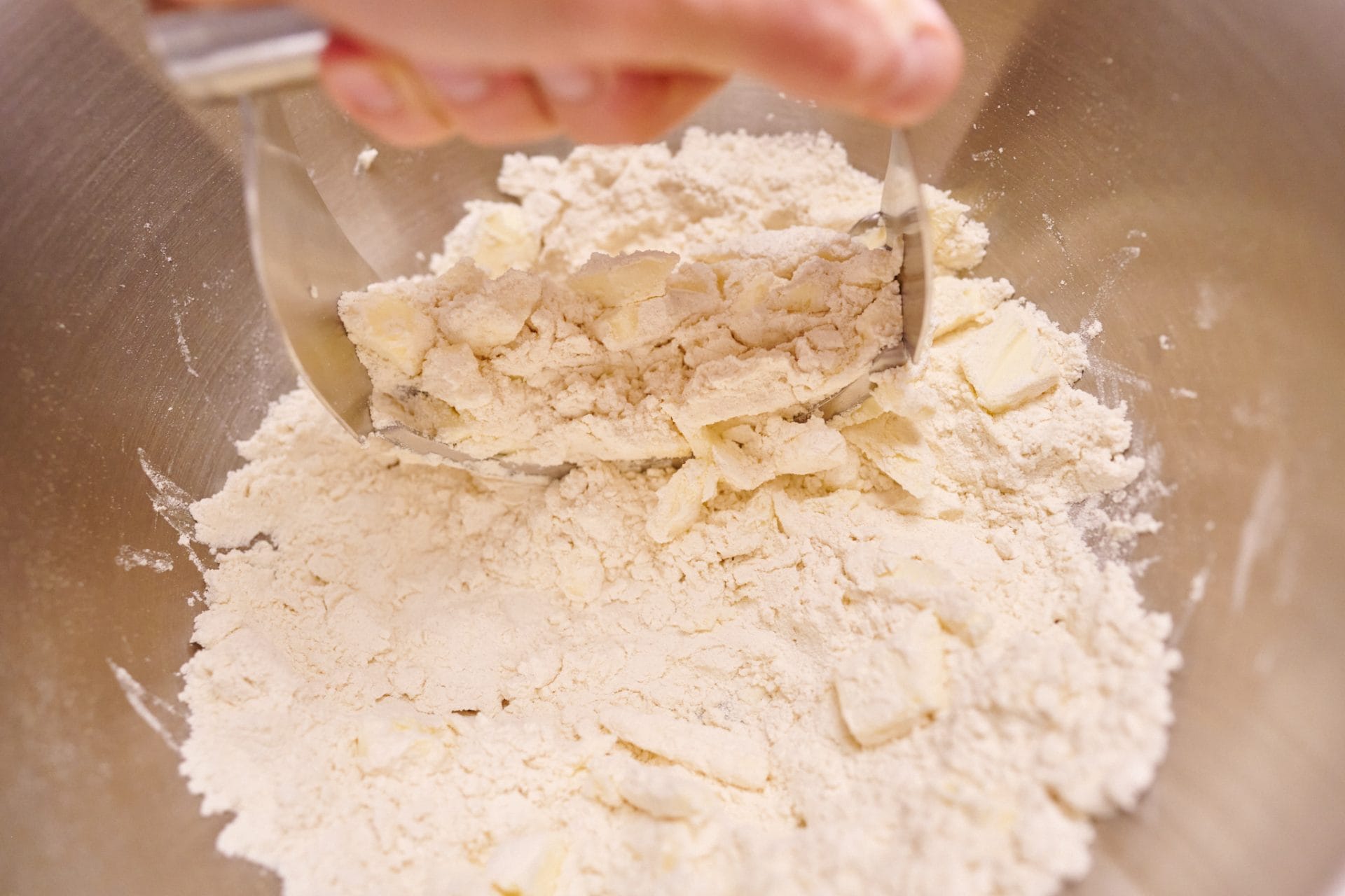 Cutting cold butter into flour with a pastry blender.