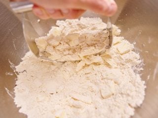 Cutting cold butter into flour with a pastry blender.