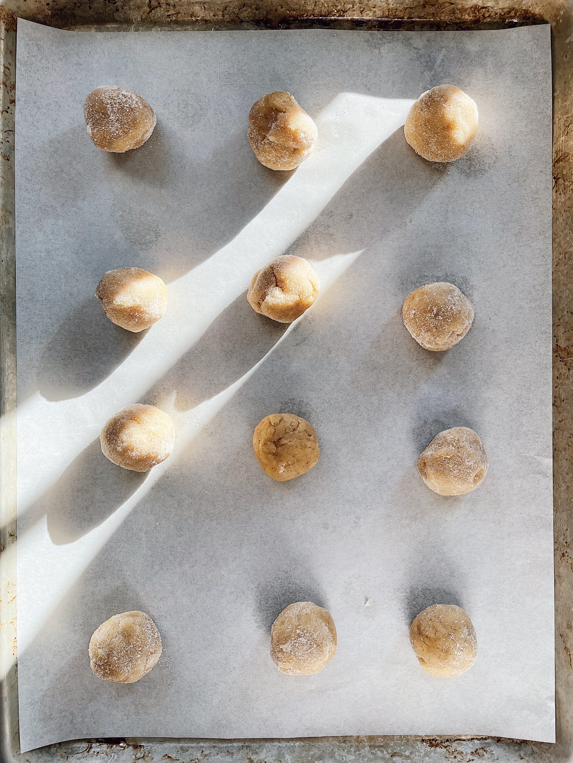 Rolling sourdough starter discard sugar cookie dough in granulated sugar.