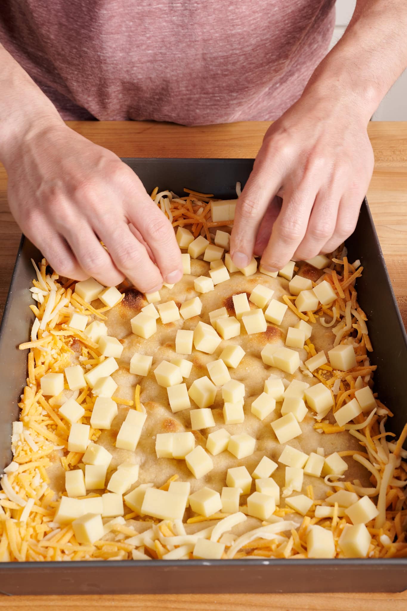 Spreading the cubed butterkase cheese over the crust.