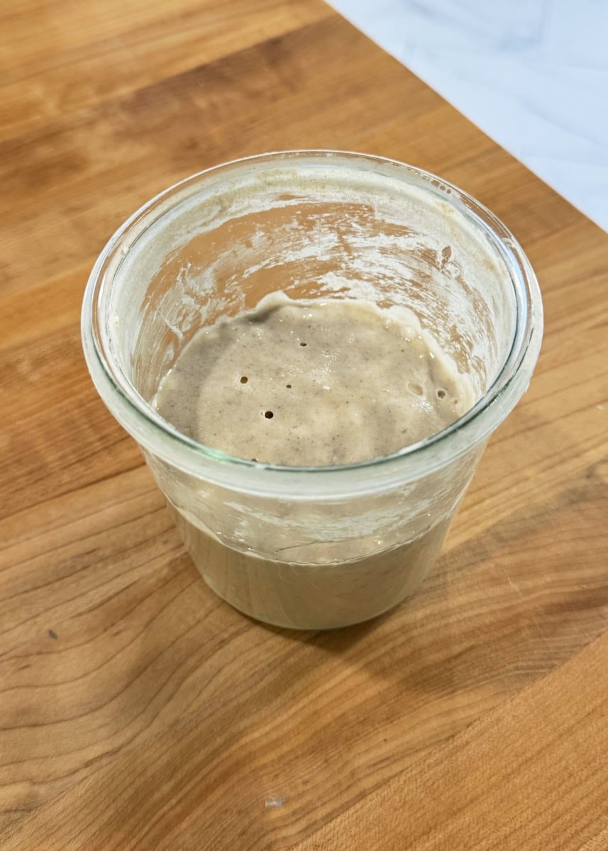 Sourdough starter from the fridge with grey flour on top.