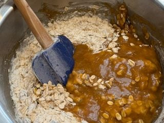 Mixing brown butter and sugar in the oats and flour mixture.