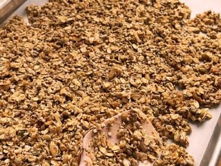 Dividing the granola mixture between sheet pans.