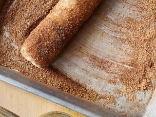 Rolling sourdough discard cinnamon toast cookies in cinnamon sugar.