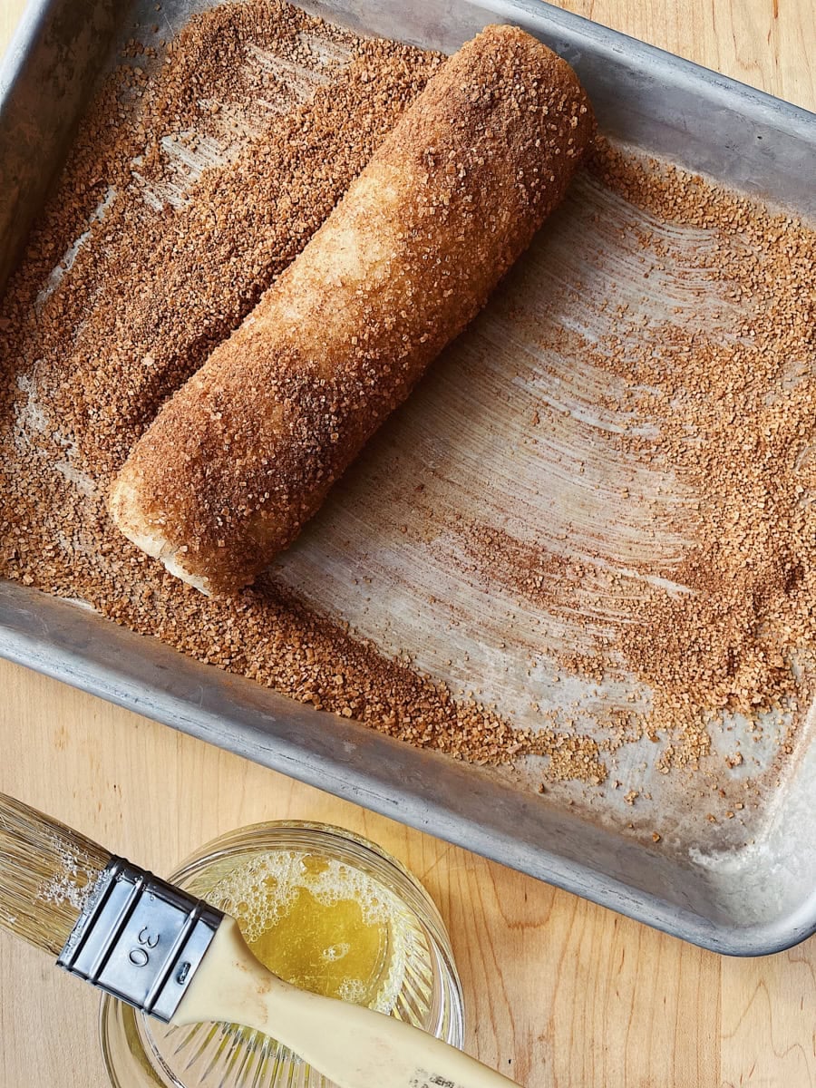 Rolling sourdough discard cinnamon toast cookies in cinnamon sugar.