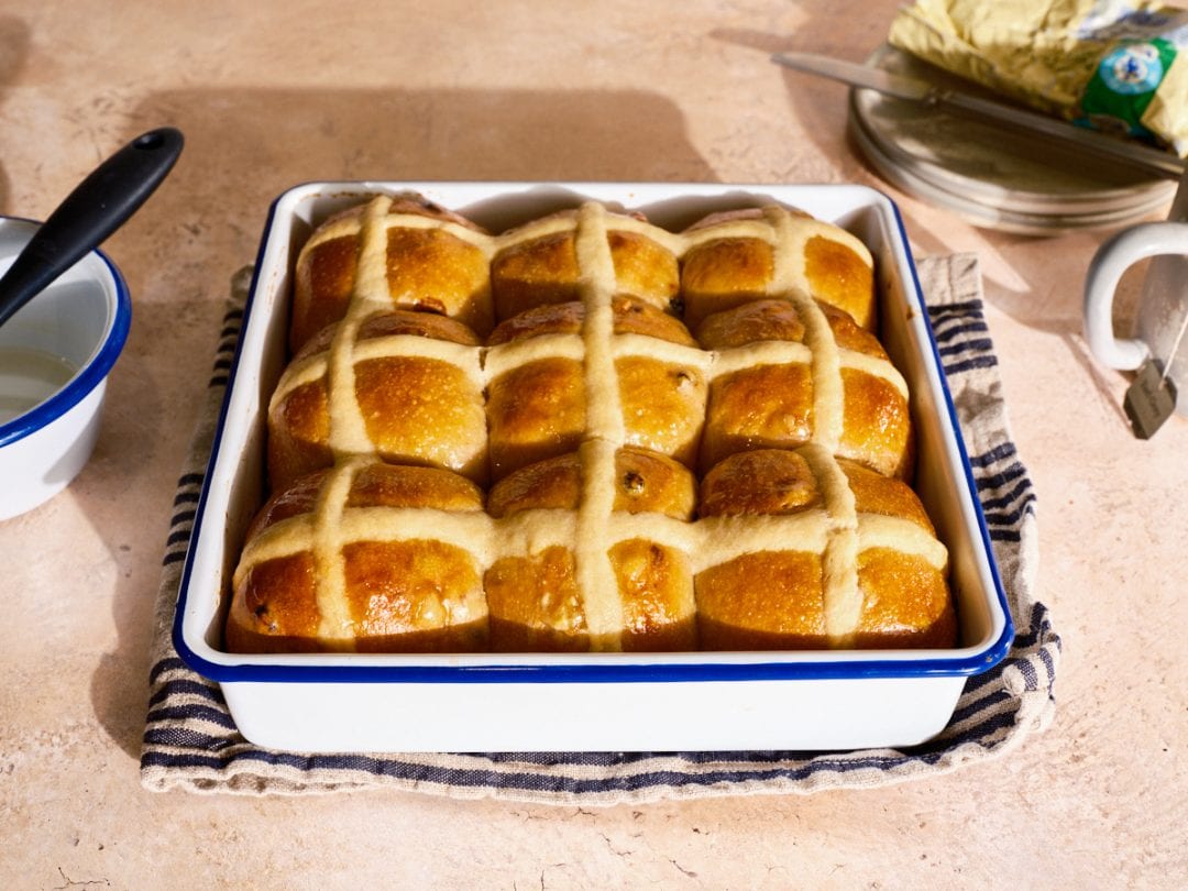 Sourdough hot cross buns baked and in a pan.